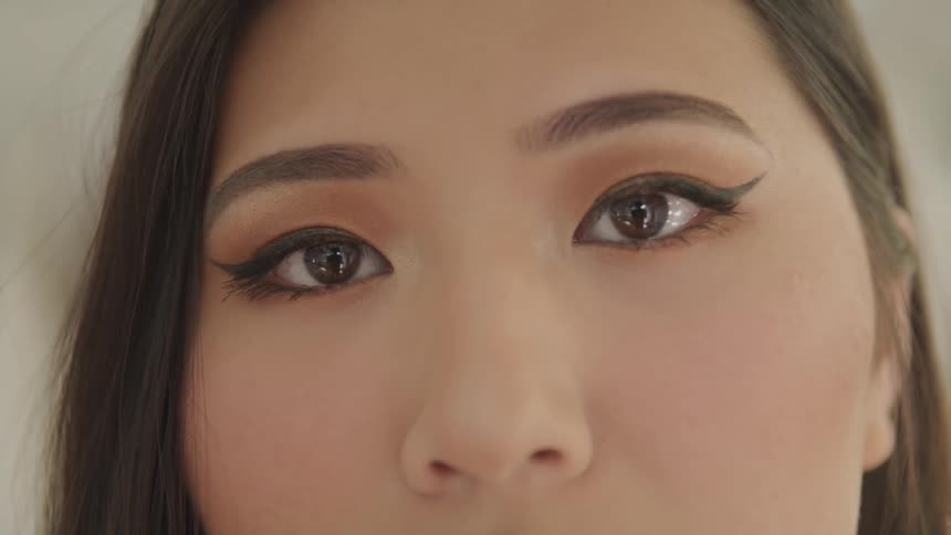 An asian woman stares into the camera