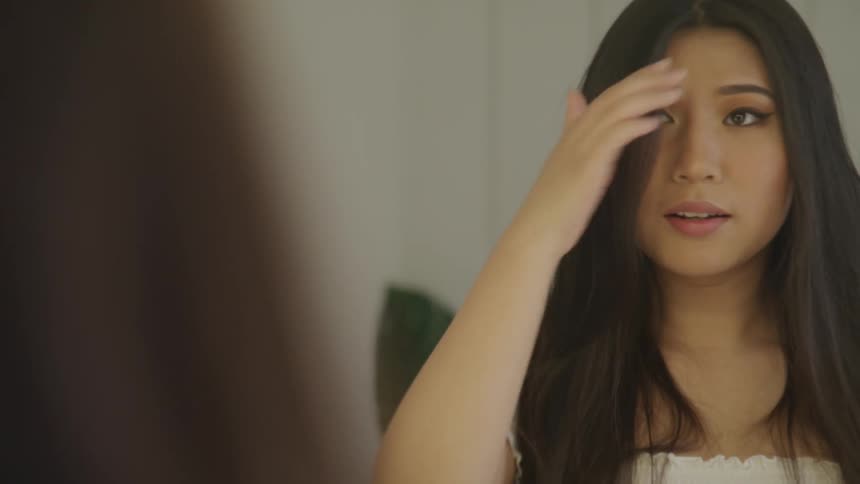 A teenage girl fixing her hair in a dressing room