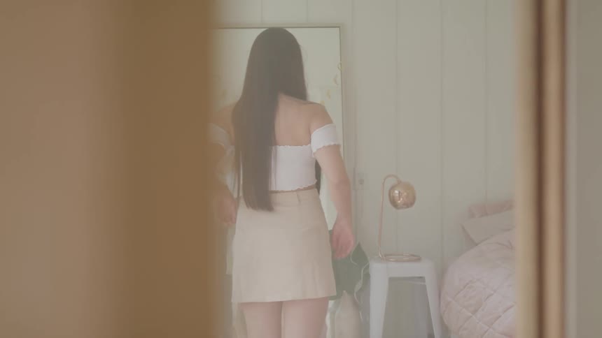 A woman poses as she checks her appearance in a body length mirror