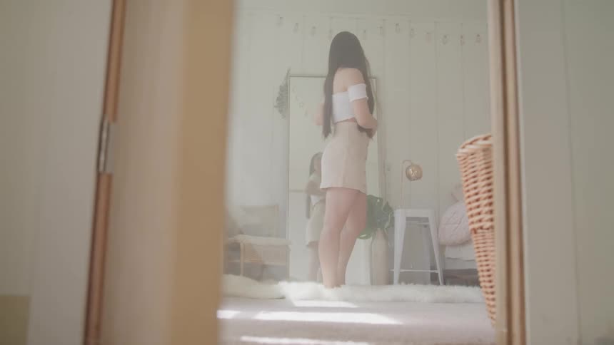 A woman with a skirt standing and posing in front of a mirror