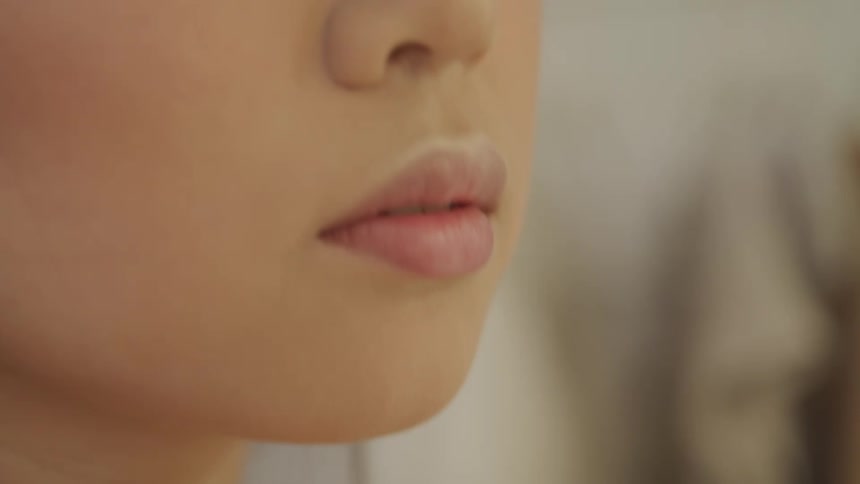 A woman touching her hair and nose and lips with her fingertips