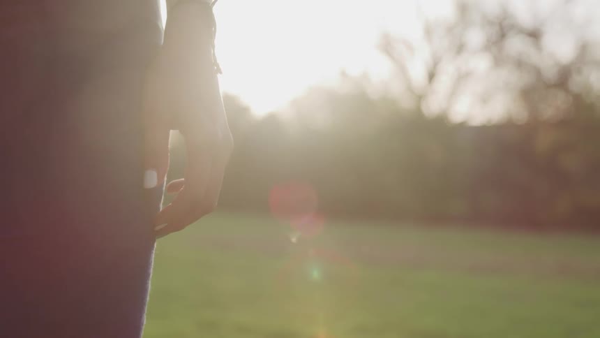 A woman standing in a grassy field while the sun shines down