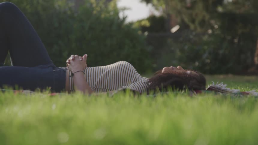 A woman is laying down on the grass in spring