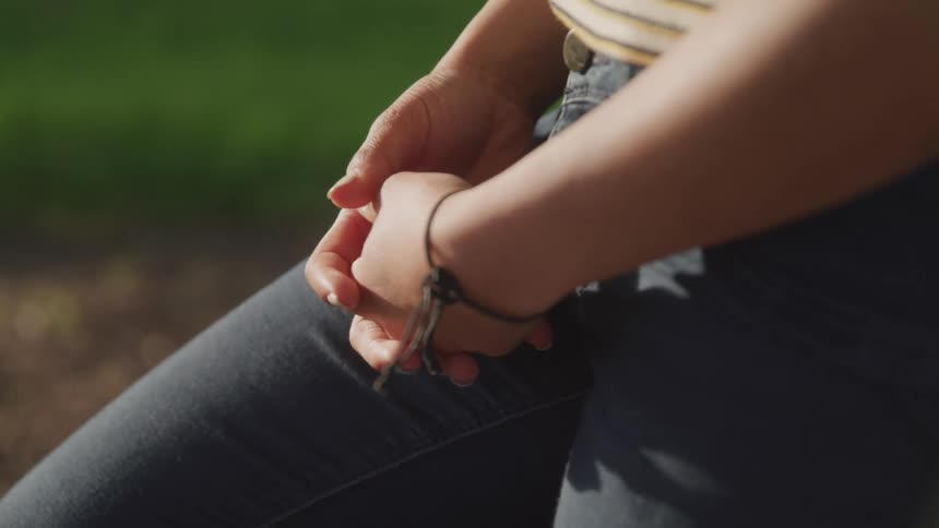 A woman with jeans sitting with dirt and grass in the background