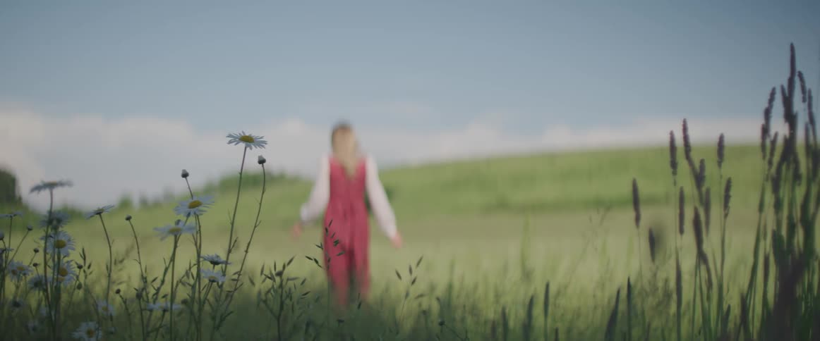 Young woman in long prairie dress walks through field