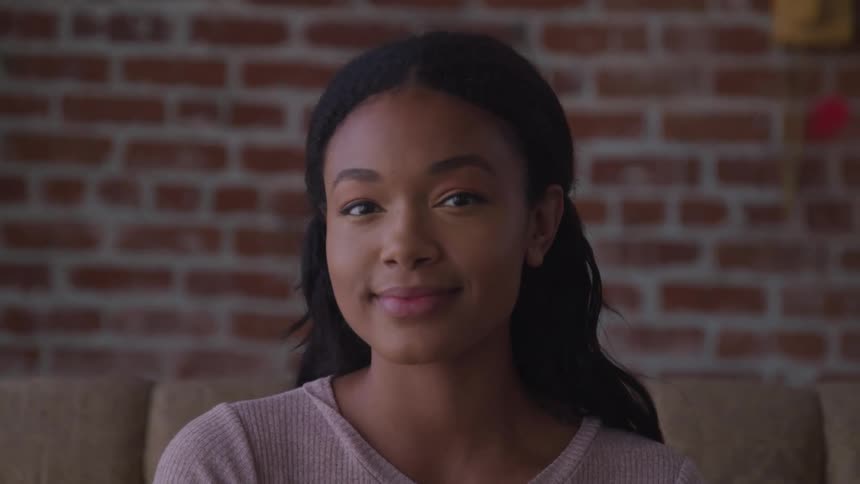 A teenage girl sitting on furniture indoors smiles