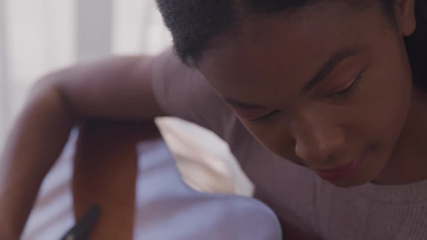 A young girl playing a guitar at home