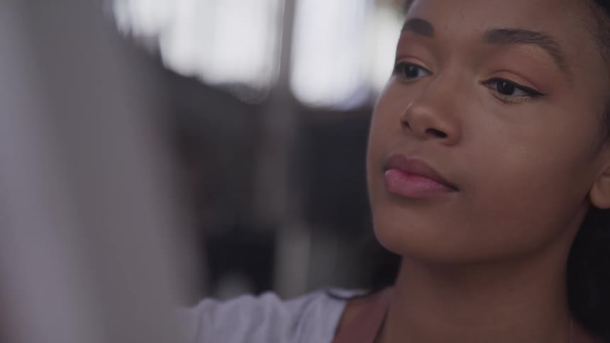 A young woman is focusing on the screen in front of her as shes sitting down