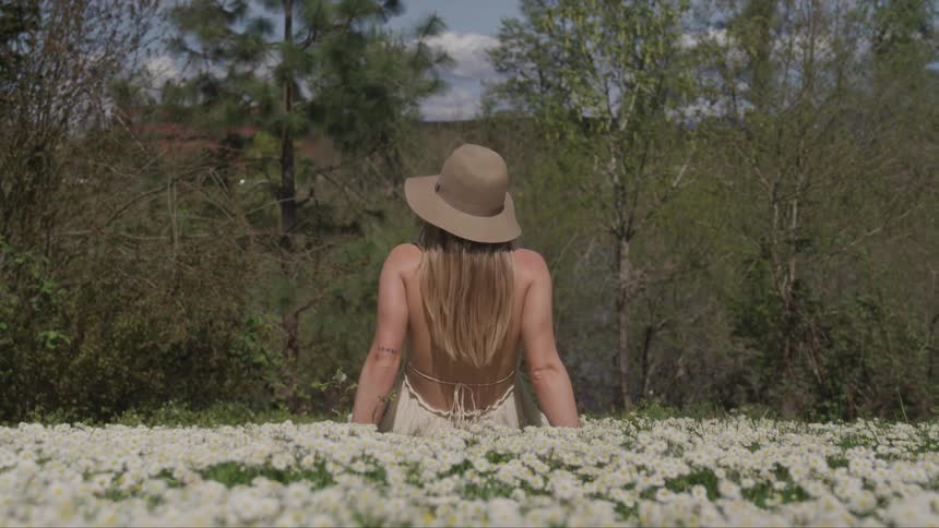 A woman is sitting outdoors in a meadow