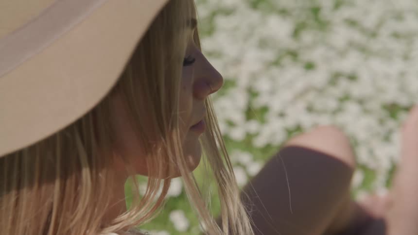 A teenage girl sits out in the sun with her eyes closed