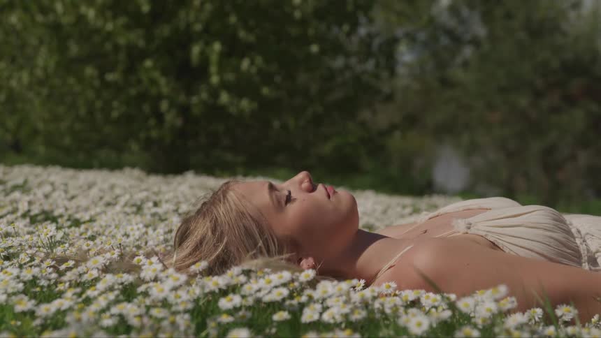 A woman is laying in a field of flowers
