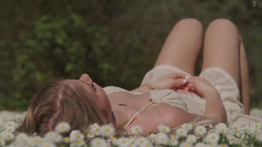 Woman lays on her back in a field of daisies