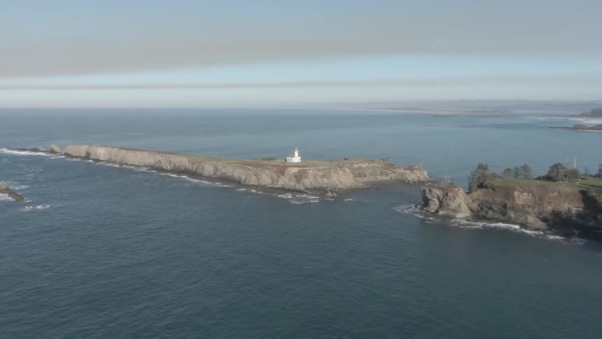 An aerial view of an ocean next to an island is displayed