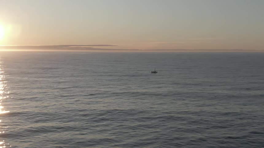 Aerial view of a boat on the calm ocean waters at sunset