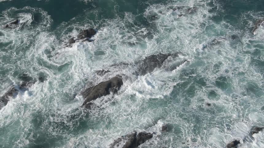 An aerial view of an ocean is displayed at midday