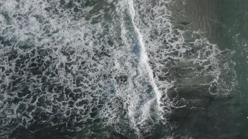 Ocean waves crash into one another on a sunny day