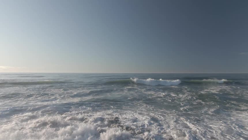 A beach with sand and waves with the sky and clouds in the background