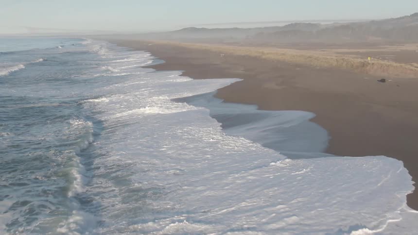 Oceans waves wash into an empty beach on a sunny day