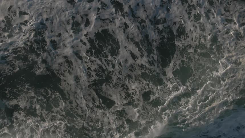 Foamy ocean waves move across the surface of the sea
