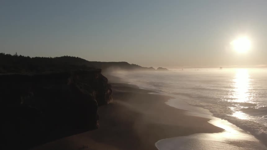 A beach coastal area with cliffs and sun flare beaming down