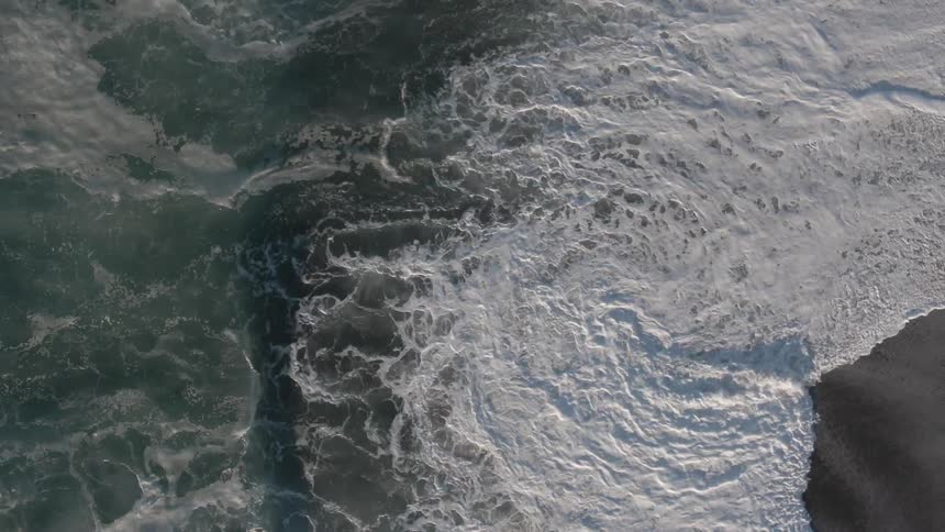 A large wave crashes onto the shore of a beach