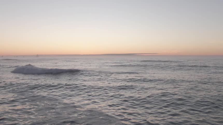 An ocean with waves and ripples in the water with the sky and clouds in the background