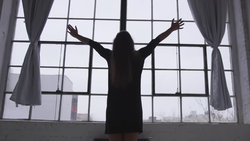 A woman stretches in front of a window at home