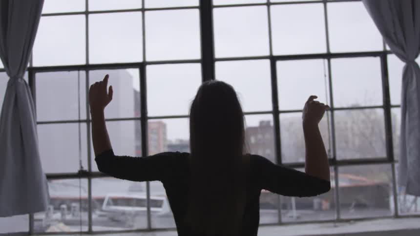 A woman dancing in front of a window