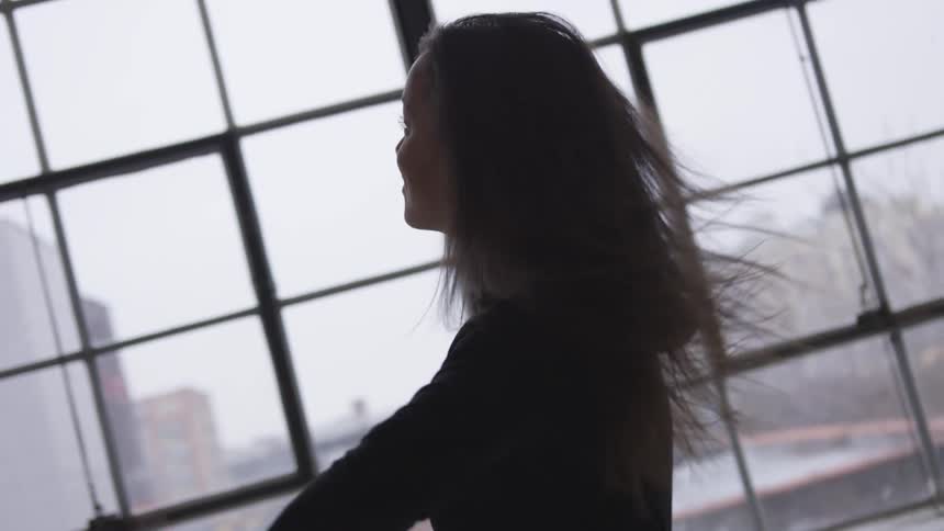 A woman at home dances in front of her window
