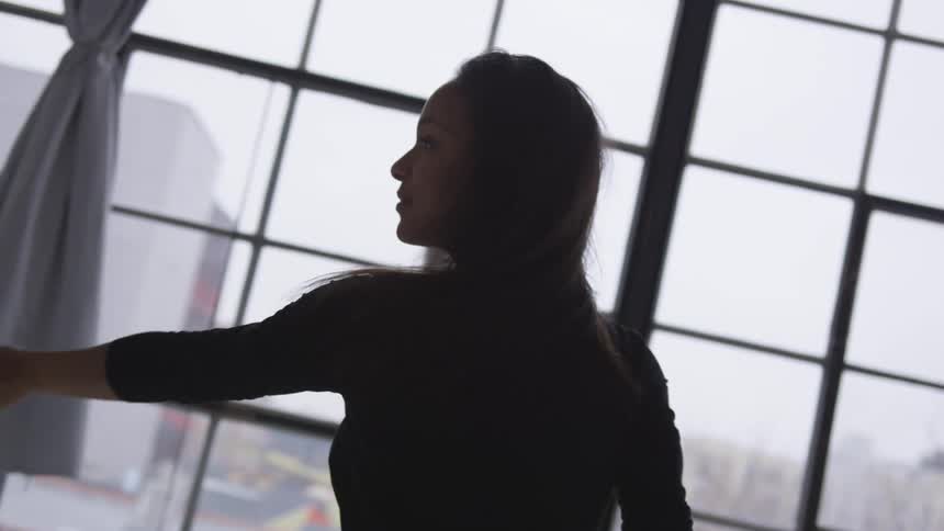 A woman is stretching near a window