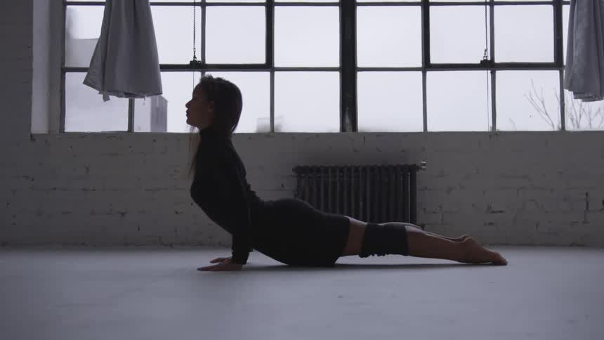 A woman on the floor stretching near a window