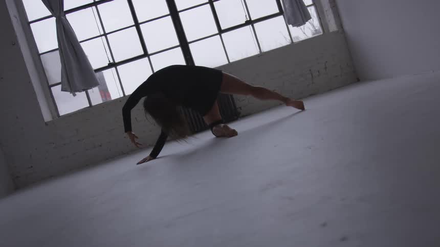 A woman is stretching in an empty room