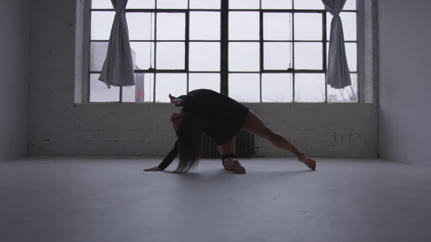 A woman is stretching in a room indoors