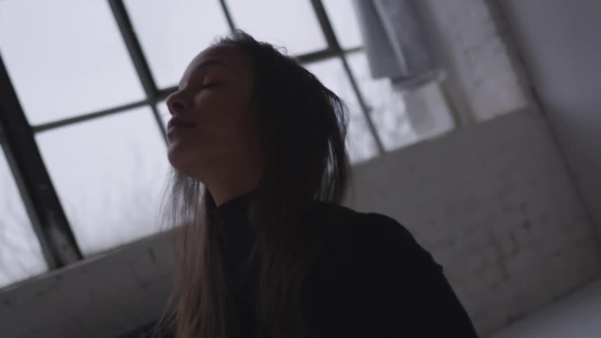 Woman performs yoga pose in white room near window