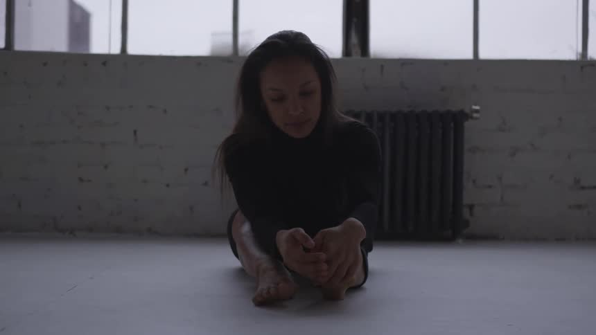 Woman sits on floor near window and radiator stretching