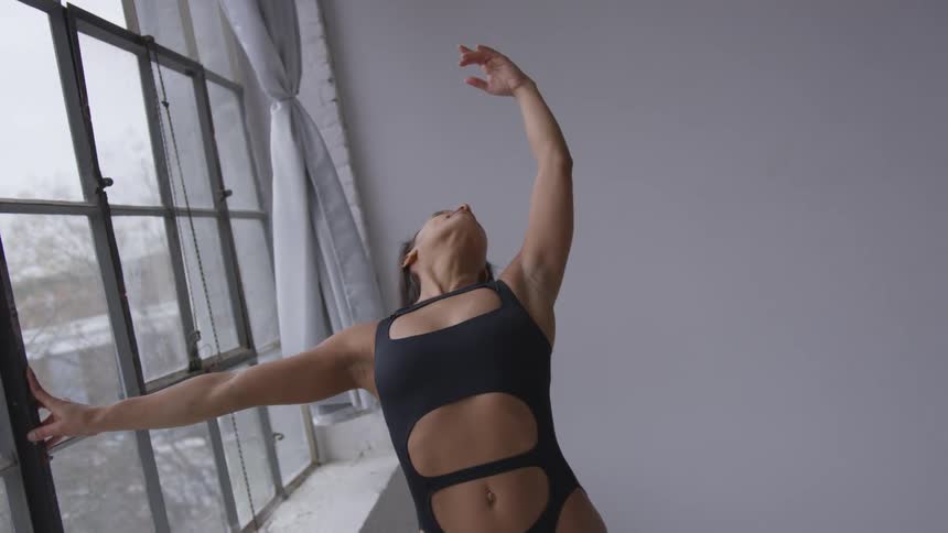 A woman is doing yoga next to a window