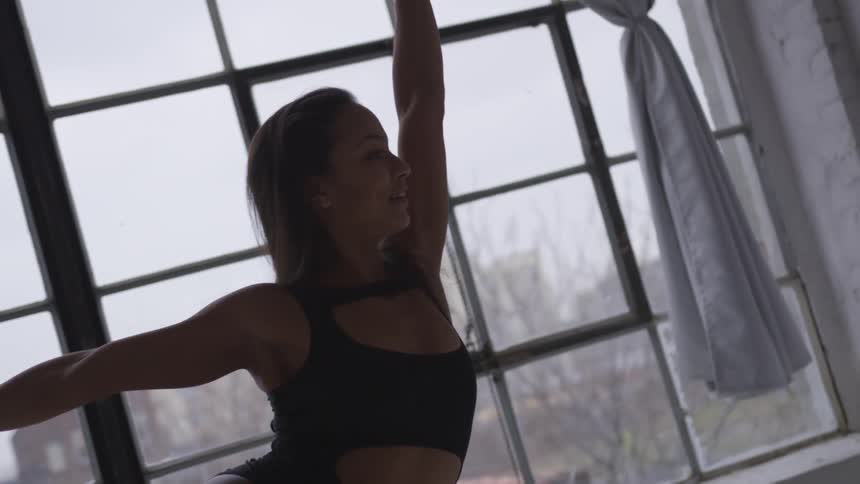 Young woman dancing in front of a window in a studio