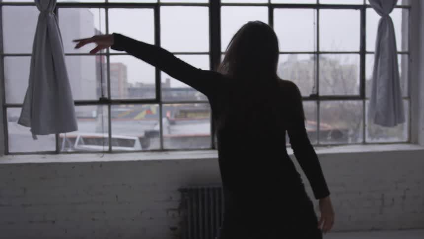 Young woman dances in the white room of a studio in the city