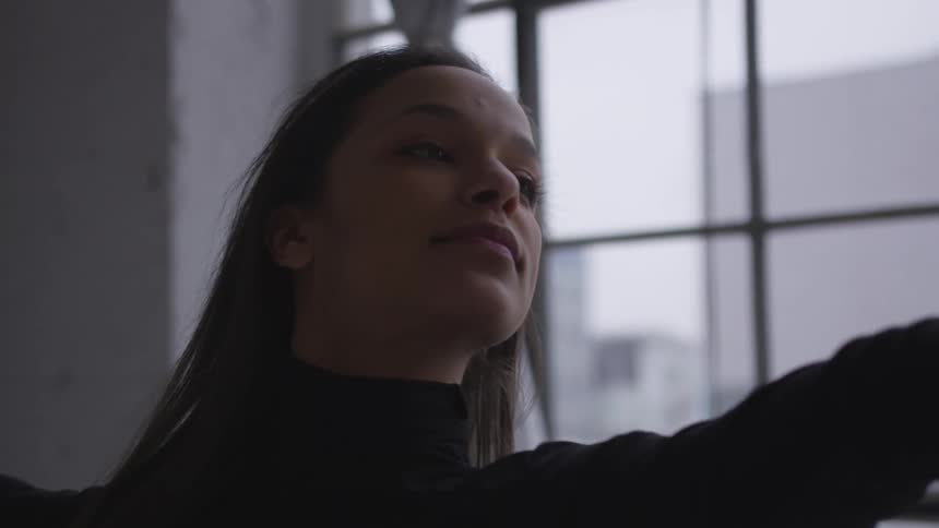 A woman dancing in front of a window