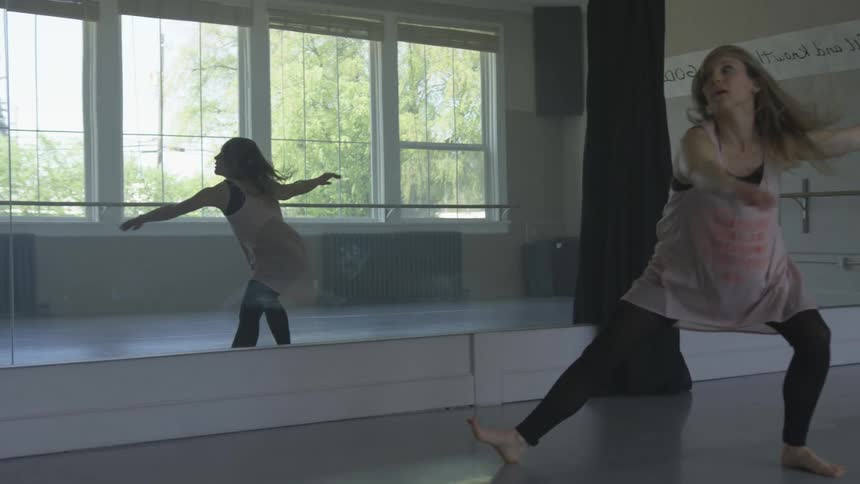 A woman performs ballet maneuvers in a ballet studio on a sunny day