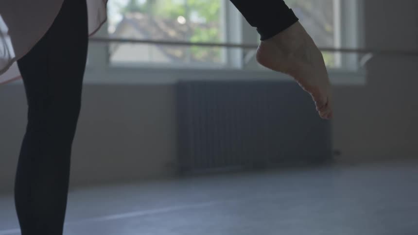 A woman is doing ballet in an empty room
