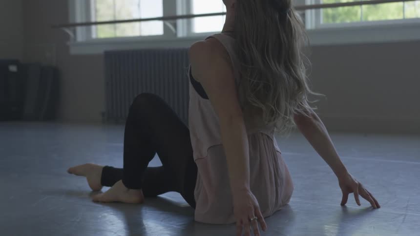 A woman is doing a dance pose in an empty room