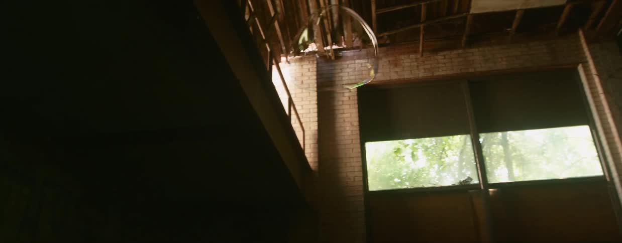 A large balloon floats within an old abandoned brick building before popping