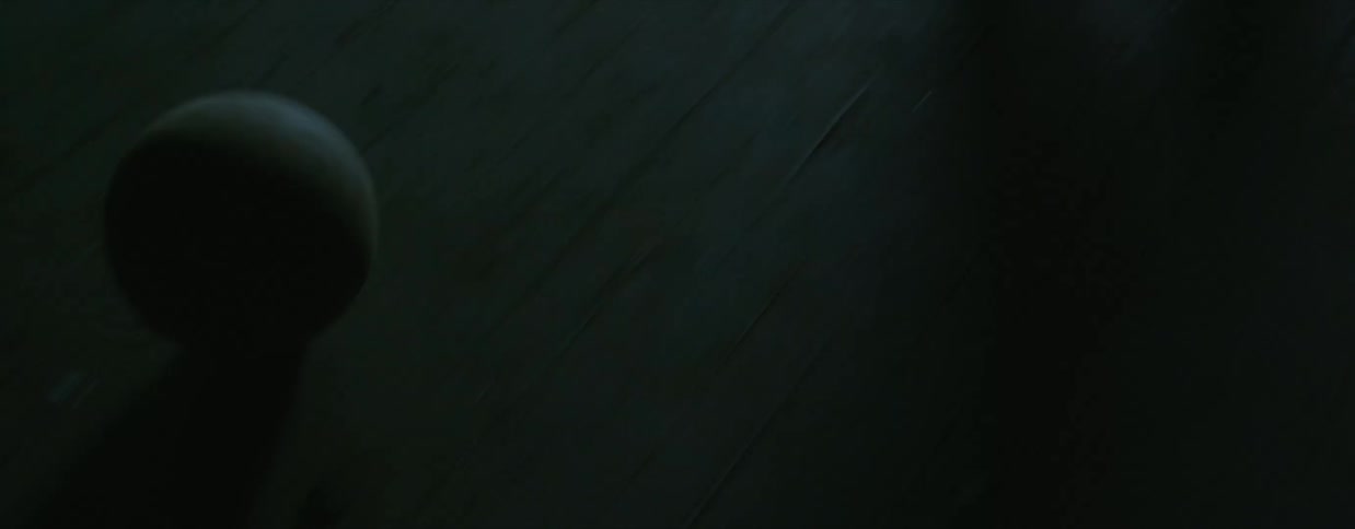 A woman wearing jeans and boots kicks a white ball across a wood floor