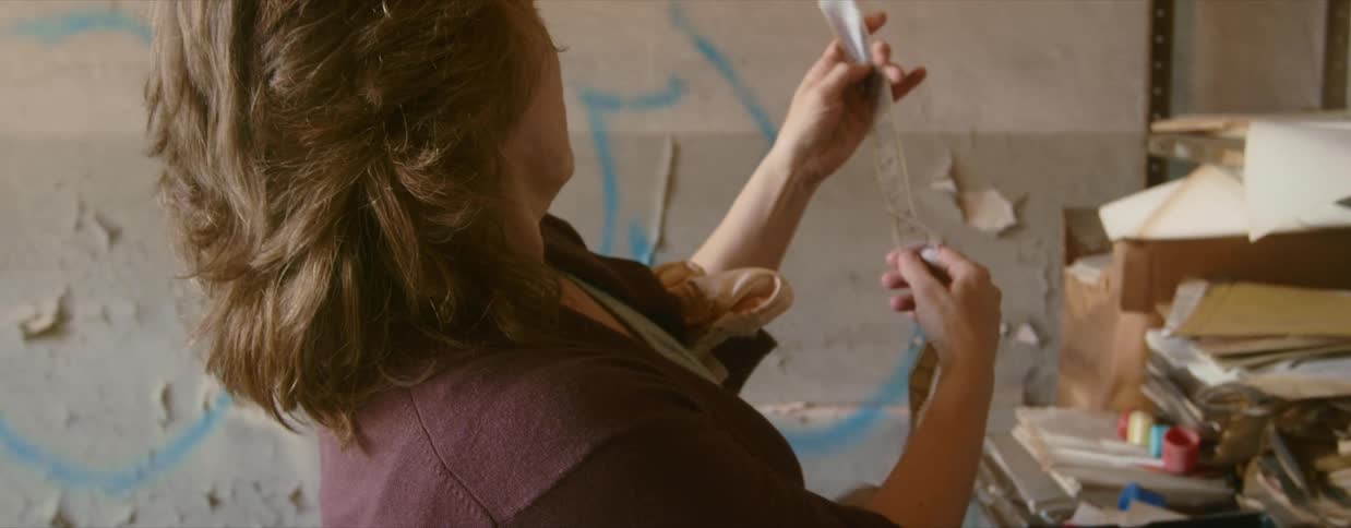 A woman looks at papers on shelves in an abandoned building