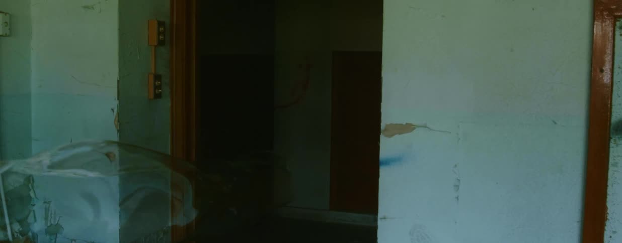A large elongated bubble floats through an inner doorway of a derelict building