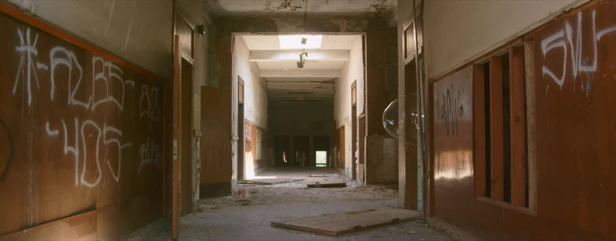 An abandoned building with an empty hallway with walls covered in graffiti and a large bubble emerges from a side opening into the hallway