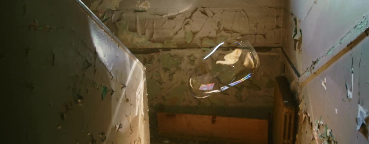A very large bubble floats along a stairwell before it pops