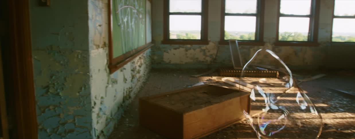 An enormous bubble floats into a room in a run down building before it pops