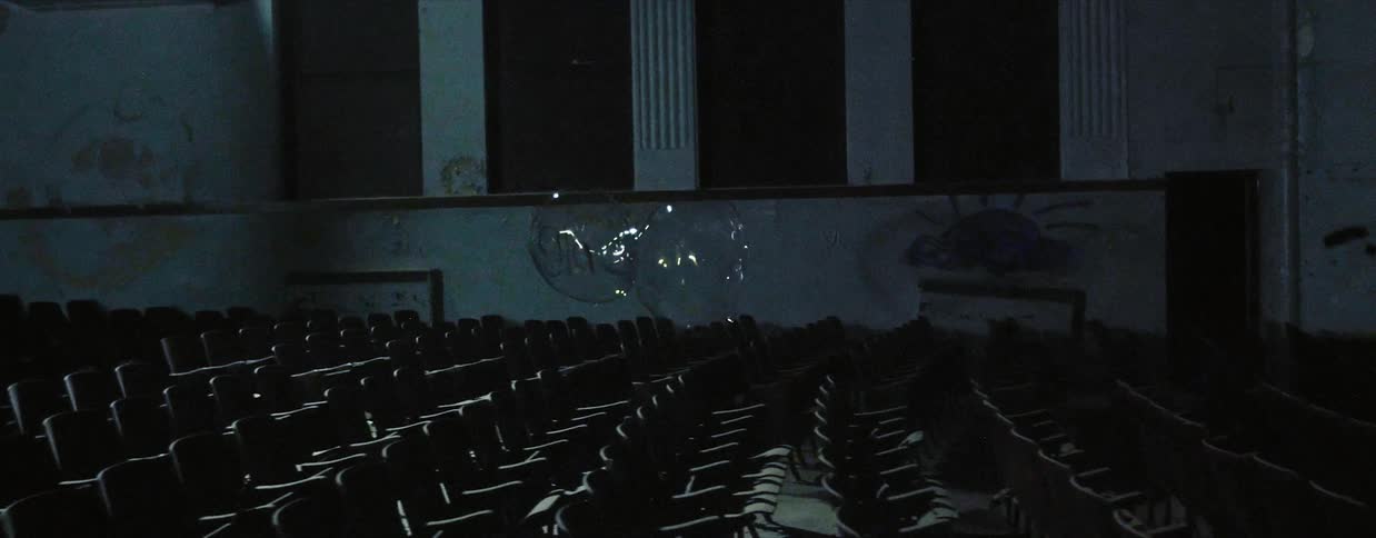 A large bubble floats in the empty theater before popping